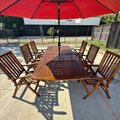 An image that captures the entire teak wood outdoor patio set with table, six chairs and a red umbrella.